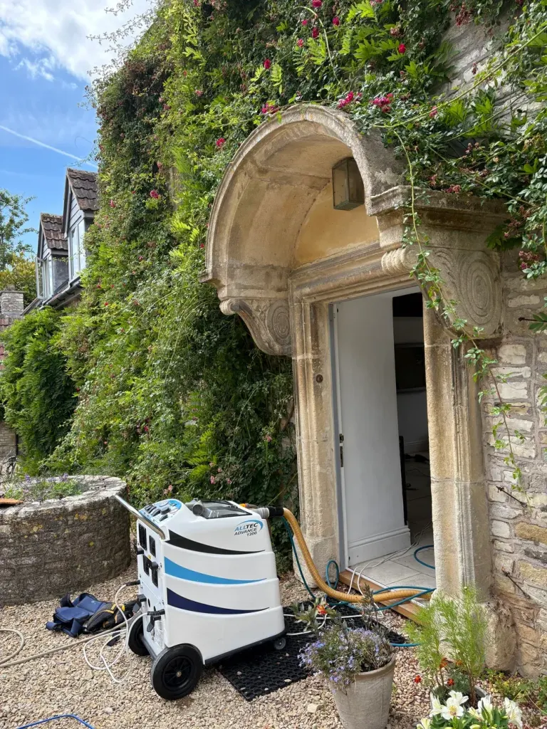 Alltec Advance 1200 hot-water extraction machine set up outside the carved stone doorway of a period stone house.