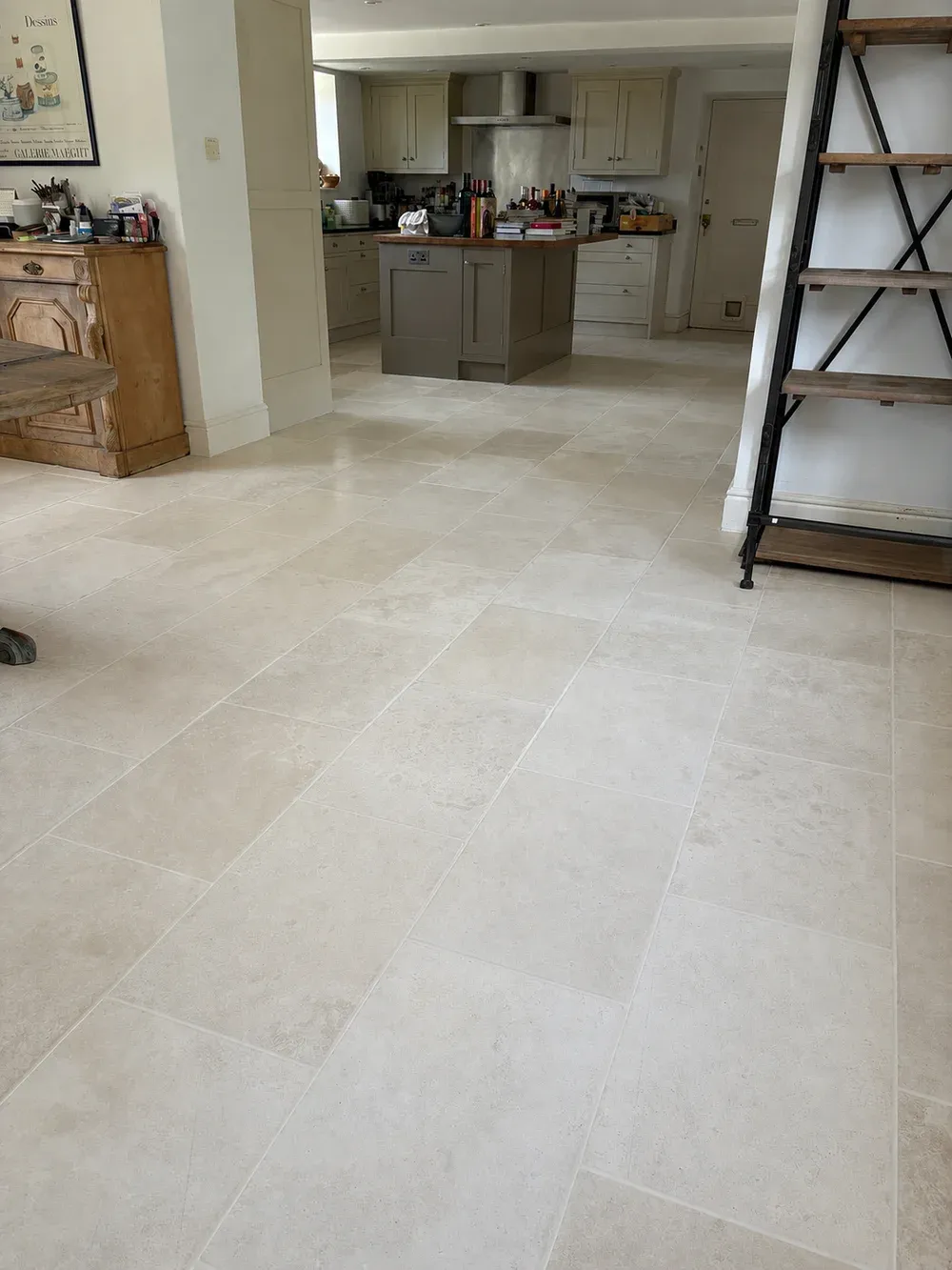 Cream limestone tile floor in an open-plan kitchen and living space, with a ladder shelving unit.